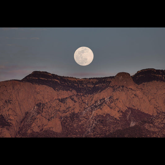 A full moon just after rising behind the Sandia Mountains. 